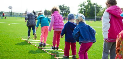 Toddler with messy hands digging in mud, engaging in sensory play that supports fine motor skill development.